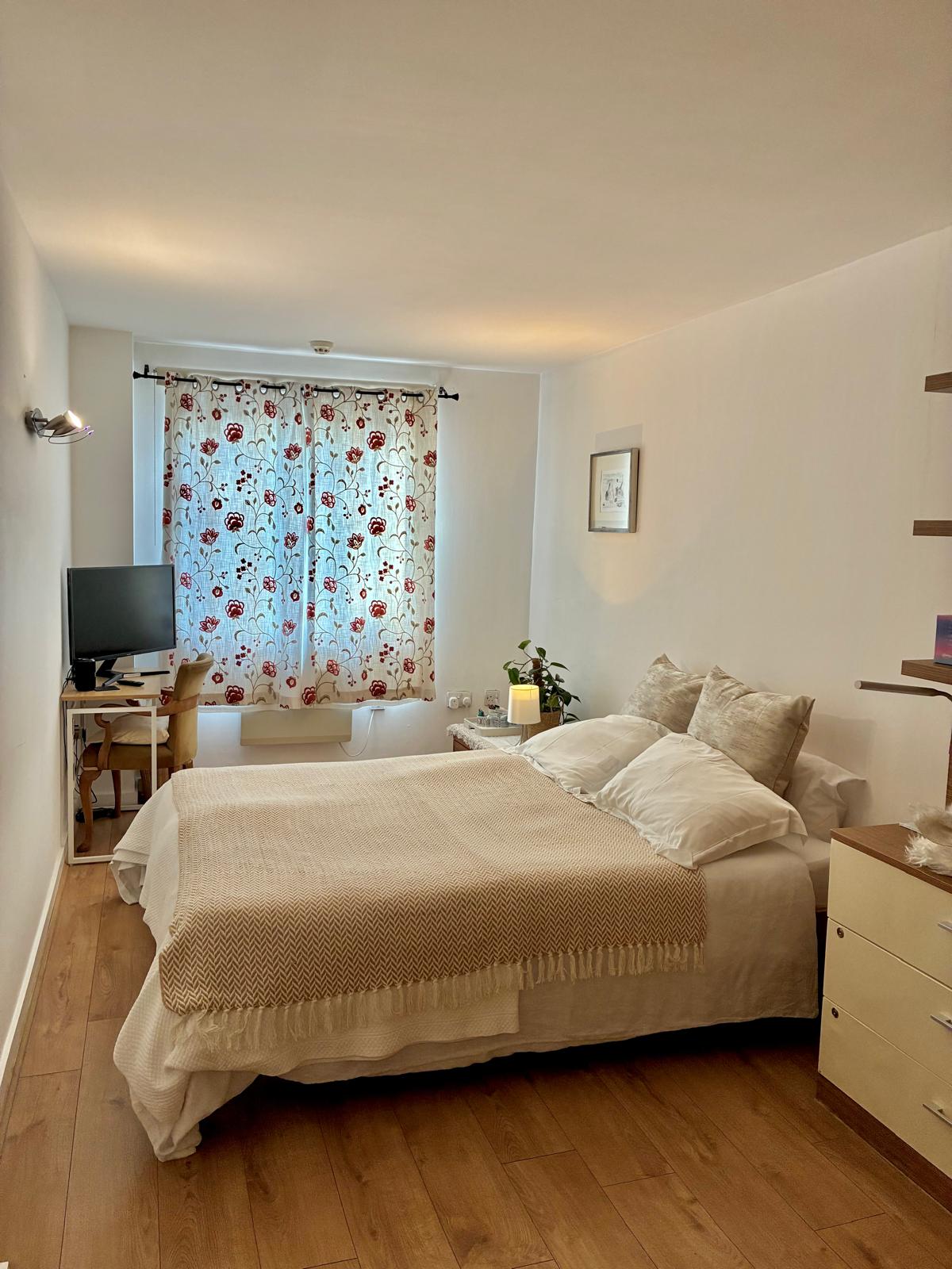 Staged bedroom with natural light and floral curtains