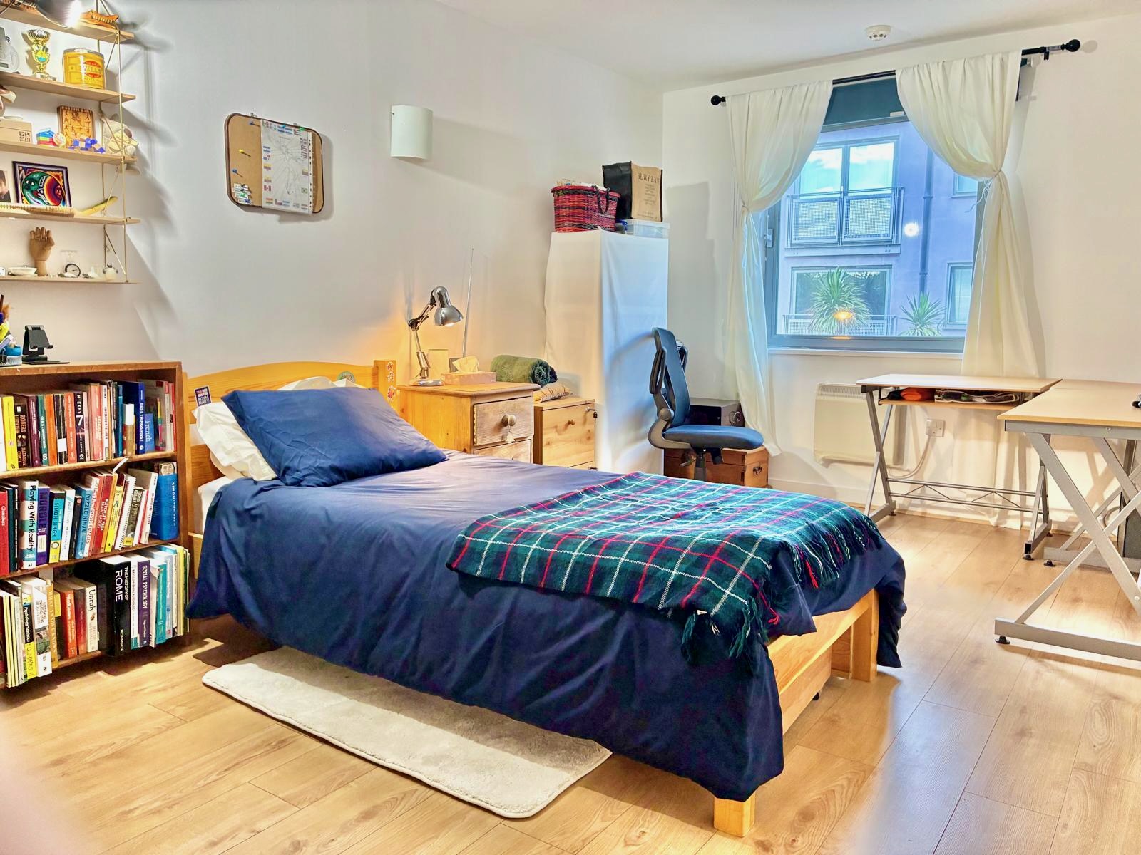 Cosy double bedroom with blue bedding and bookshelf